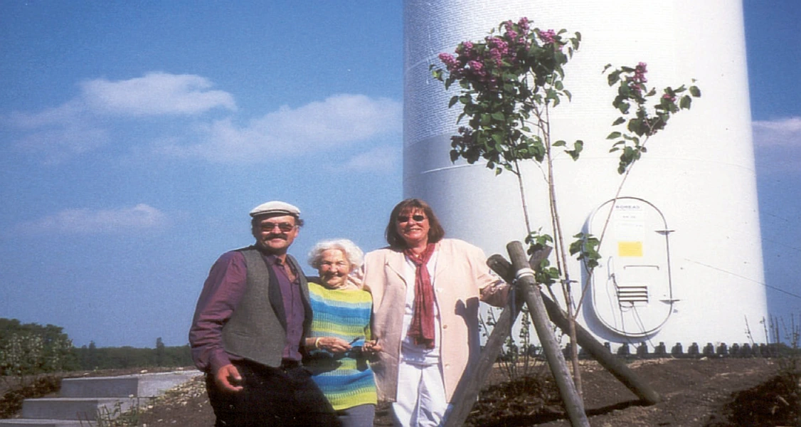 Drei Personen stehen am Fuß des Windrades des Projektes