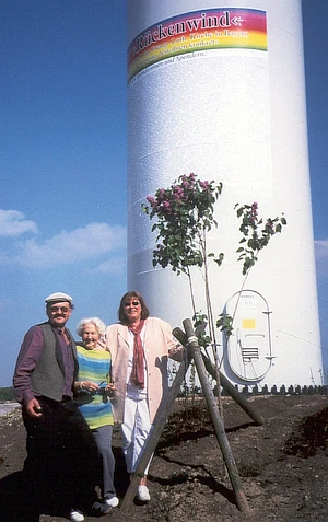 Drei Personen stehen am Fuß des Windrades des Projektes Rückenwind